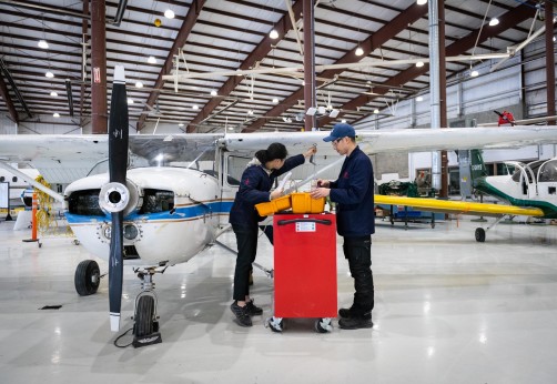 Two Aviation Technician Avionics Maintenance students working in front of airplane in Jazz Hangar at Fanshawe College