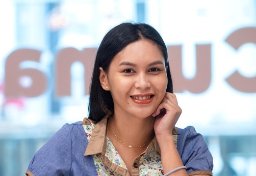 Student smiling at camera sitting at desk