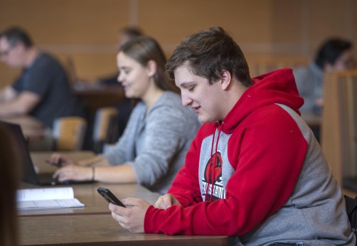 Fanshawe student sitting in cafeteria looking at mobile device