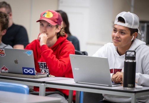 students sit in a classroom smiling