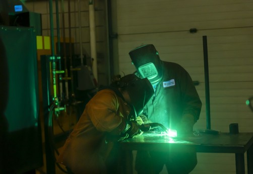 welders lean over their work lit by green welding light