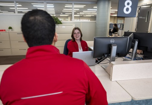 student stands in office of registrar talking to staff