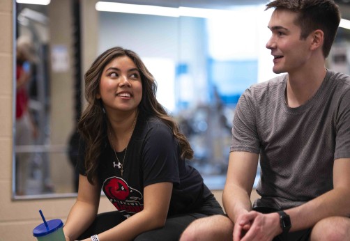 Two students speaking to one another while at the student wellness centre gym