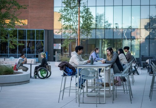 Fanshawe students sitting on raised tables within the Innovation Village courtyard