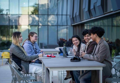 Five Fanshawe students sitting at a table outside of innovation village