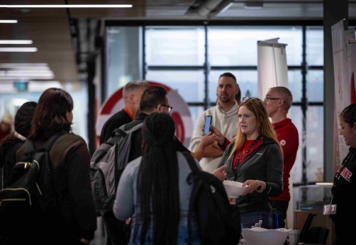 A Fanshawe employee speaking with a student in a crowded environment at the pathways fair