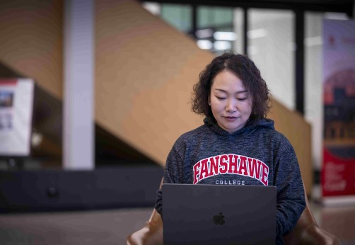 A student sitting in innovation village on their laptop
