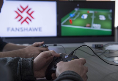 Hands holding an xbox controller with the screen in the background