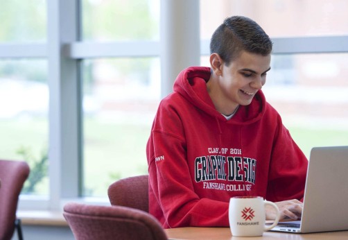 A student sitting in the cafeteria working on their laptop