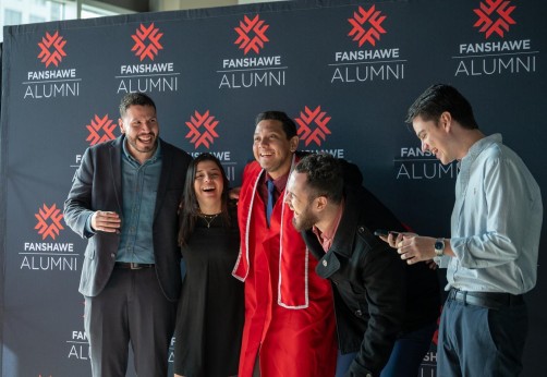 Fanshawe College graduates pose in front of a Fanshawe Alumni backdrop at Canada Life Place during Convocation in London, Ontario.