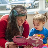 Early childhood educator reading to toddler in daycare setting