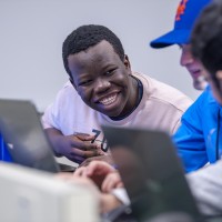 Students happily chatting and working on laptops in computer lab