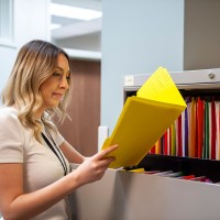 Office administrator looking at a yellow folder in a filing cabinet