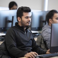 Business and Information Systems Architecture student, in class, working on computer