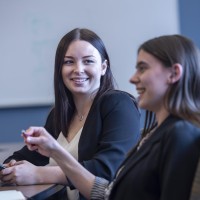Two smiling Fanshawe business students, collaborating in a conference room