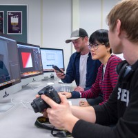 Three students with cameras and computer