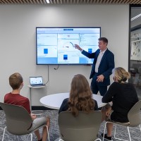 Group of three people watching a presenter and screen