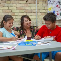Child and Youth worker, chatting with two young people who are colouring