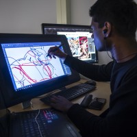 Student in computer lab, drawing a character on a display tablet