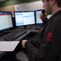 Guy sitting in front of screens with walkie talkie