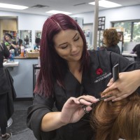 Hairstyling student in hair salon lab, cutting the hair of a client