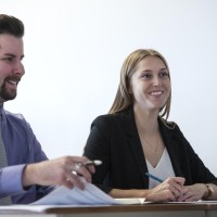 Business students in classroom, collaborating and smiling