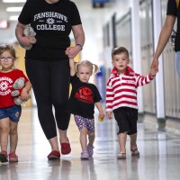 Three children walking down hallway, holding hands with three adults