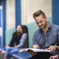 Fanshawe students sitting in hallway looking at textbook