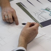 Two hands pointing to parts of an urban design rendering