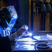 Welding student with helmet on and sparks flying