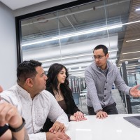 A male leadership and management student leading a team of students on a class project.