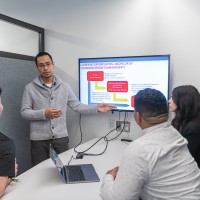 A male leadership student presenting a class project to his team of fellow students
