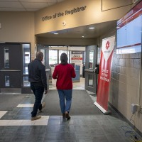 two people walk together into Fanshawe's Office of the Registrar