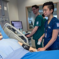 two healthcare students work with high tech patient simulator mannequin