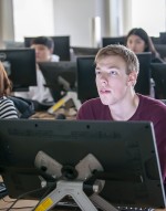 Student in busy computer lab listening to professor