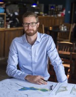 Alex Waffle sits at table with environmental design paperworks