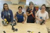 Female students working in carpentry shop with woodworking equipment