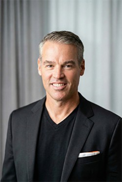 Photo of Ryan Aarts posing for a photo wearing a black suit