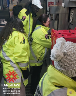 Four people in reflective coats smiling and sorting supplies