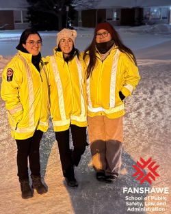 Three students in reflective coats standing in the snow and smiling