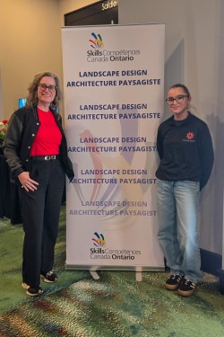 Two women stand next to a Skills Ontario banner