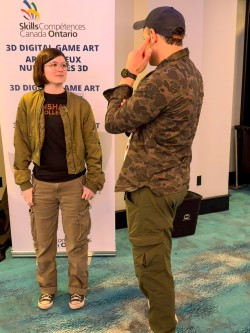Two people talk in front of a Skills Ontario banner