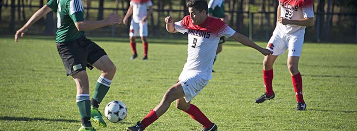 two men kicking at a ball in soccer