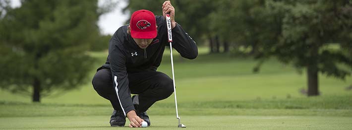 man lining up a golf ball and his golf club